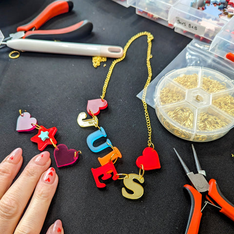 A Jewellery Workshop attendee working on a colourful name necklace saying Jules