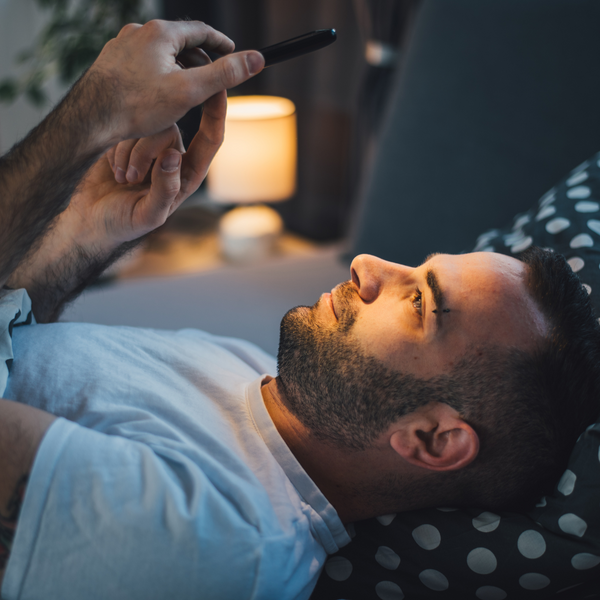 man staring at phone in bed