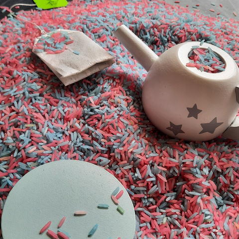 A messy makes tea party with blue and pink sensory rice and tea bags 