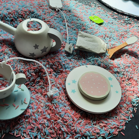 Blue and pink sensory rice with a wooden tea set on a messy play tray