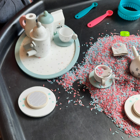 Blue and pink sensory rice combined with a wooden tea set on this tea party themed messy makes tray