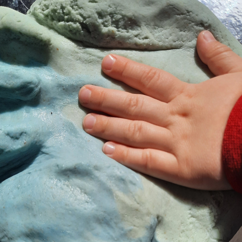 Toddler's hand making a print in the peppermint scented playdough