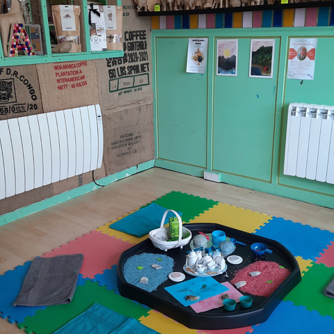 A tuff tray on colourful mats in the Art Attack Studio with a tea set and messy play materials