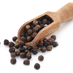 black pepper in a wooden spatula on a white back ground