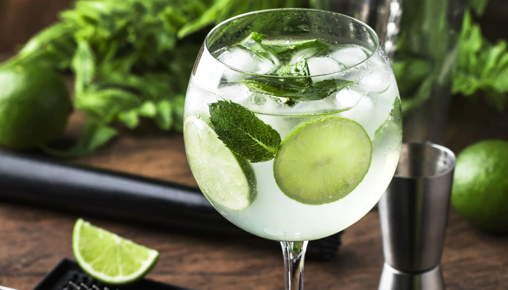 Taça de Mojito com limão ao lado e temperos ao fundo