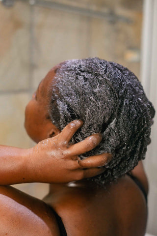 femme-noire-se-douchant-et-appliquant-un-soin-capillaire-dans-ses-cheveux