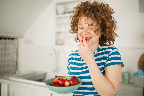 jeune-femme-aux-cheveux-bouclés-mangeant-des-fraises