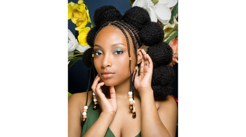 femmes noire aux cheveux crépus long coiffée de plusieurs couettes formant des meches de cheveux en forme de ponpon par Saison des Pluies la marque de produit capillaires pour femmes aux cheveux afros.