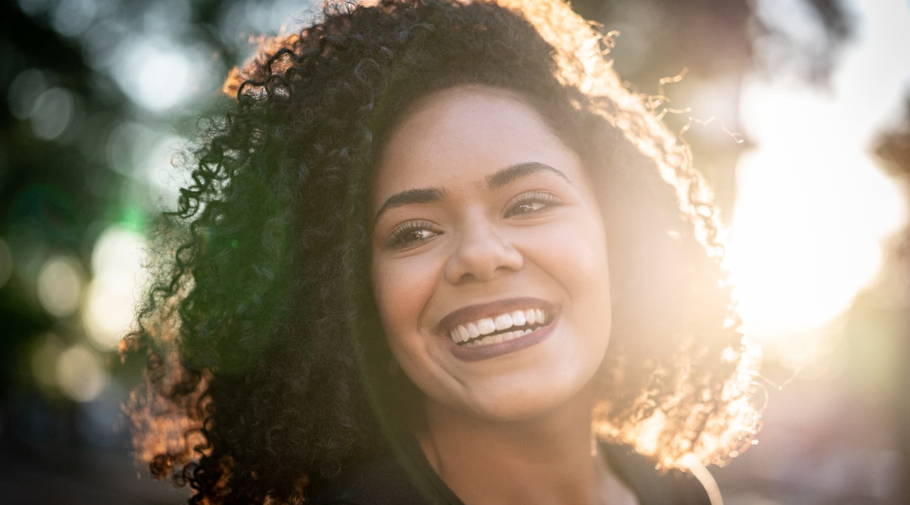 femme métiss aux cheveux bouclés dans un halo de soleil