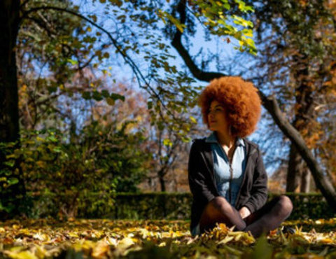 femme noire avec un afro naturel assise dans un parc