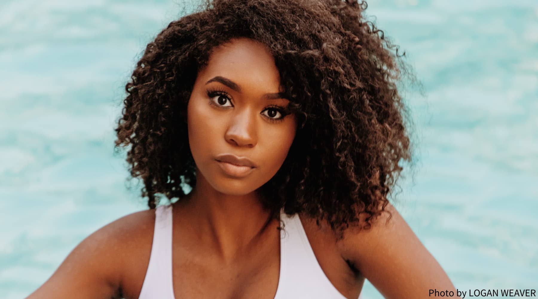 femme noire aux cheveux crépus bouclés portant un débardeur blanc. Saison des pluies