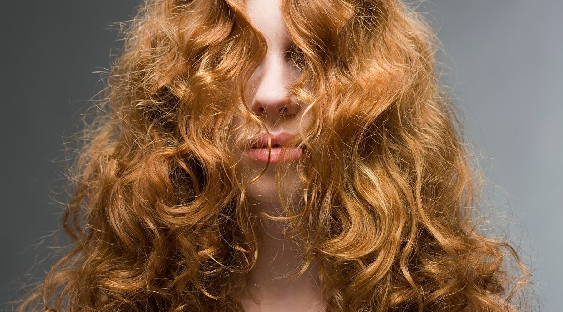 femmes rousse aux cheveux bouclés ondulés longs dont le visage est caché par ses cheveux saison des pluies