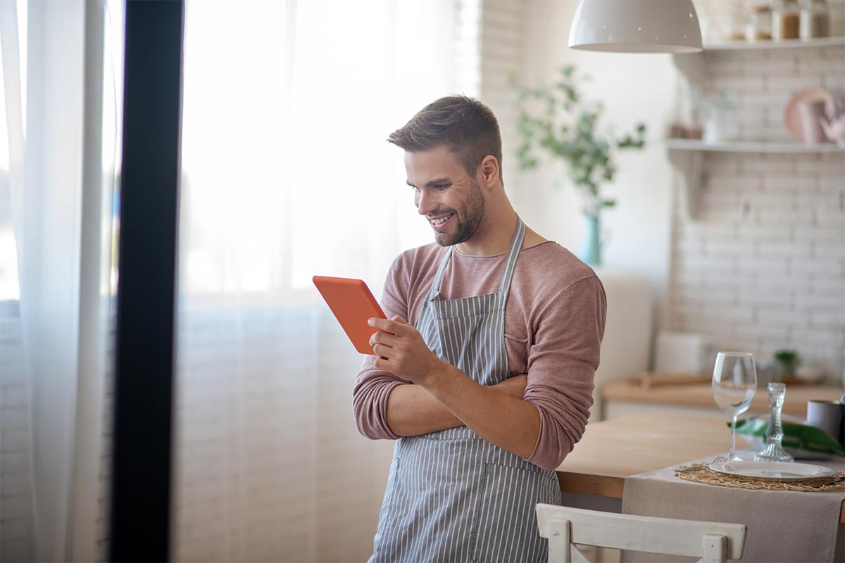 Mann steht in der Küche und liest Online Magazin