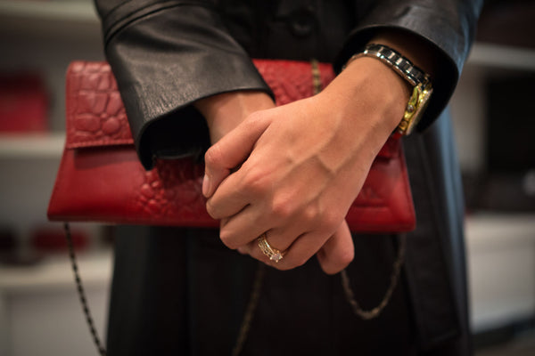 Woman in classic black leather coat with red clutch handbag - leather lasts longer