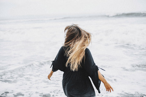 Woman turning toward the ocean with blonde hair facing the horizon