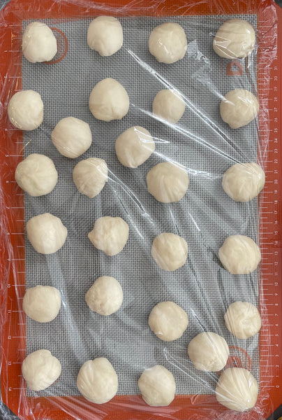 Steam bun dough in small circles on baking sheet covered with cling wrap