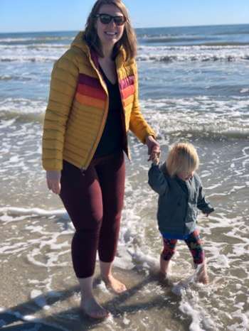 Lauren and daughter walk together along the coast