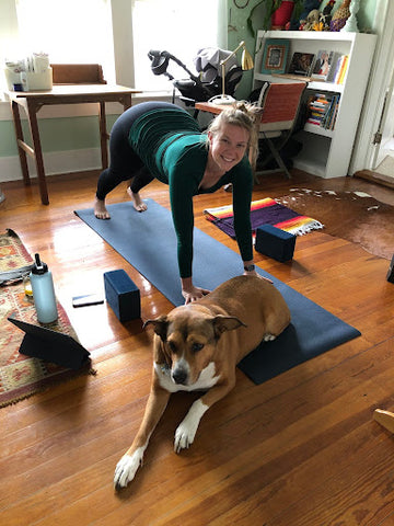 Woman does yoga at home with a dog on the mat