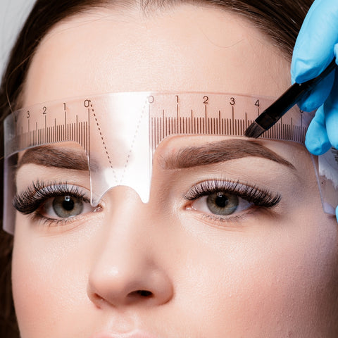 Microblading artist crafting brows with brow ruler