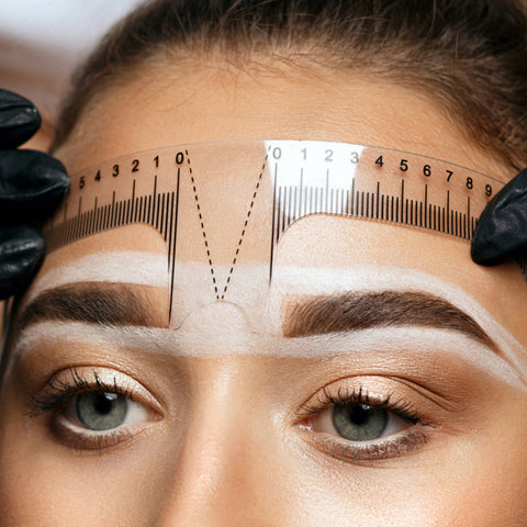 PMU artist measuring the brow of a client and mapping for microblading procedure