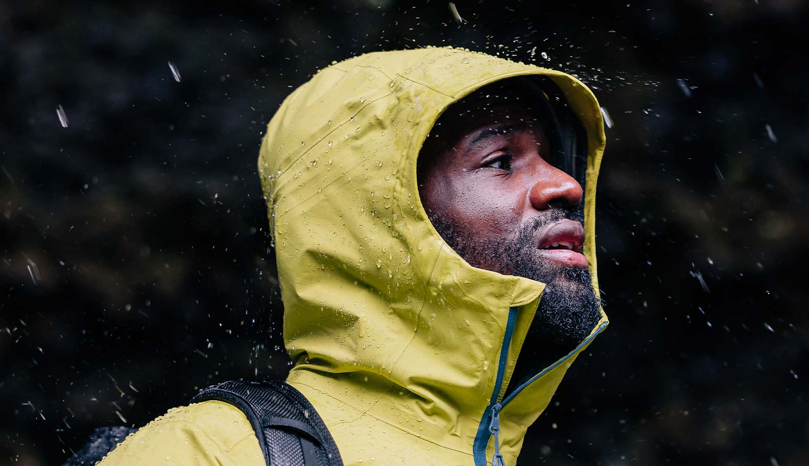 man-with-waterproof-standing-under-rain-jacket-beading