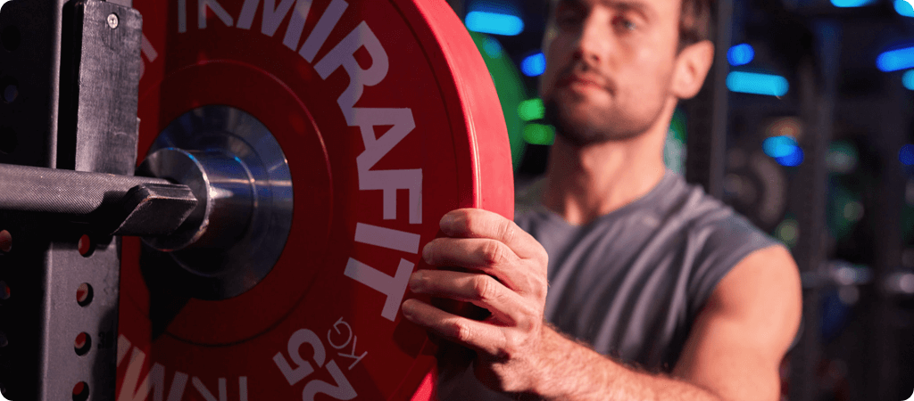 man adding weights to a barbell for weightlifting