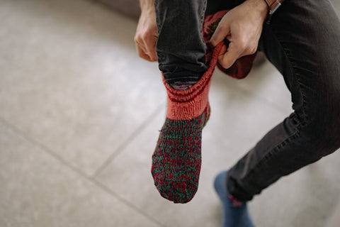 a person putting on warm woollen socks on a cold floor