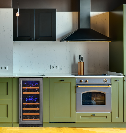 A black cabinet, stainless-steel trimmed door dual zone wine cooler set in an undercounter built-in setting with green-theme cabinetry