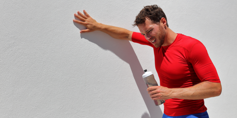 Athlete leaning against wall, exhausted from dehydration