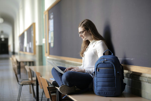 Girl Sitting Doing Homework with Backpack and Laptop