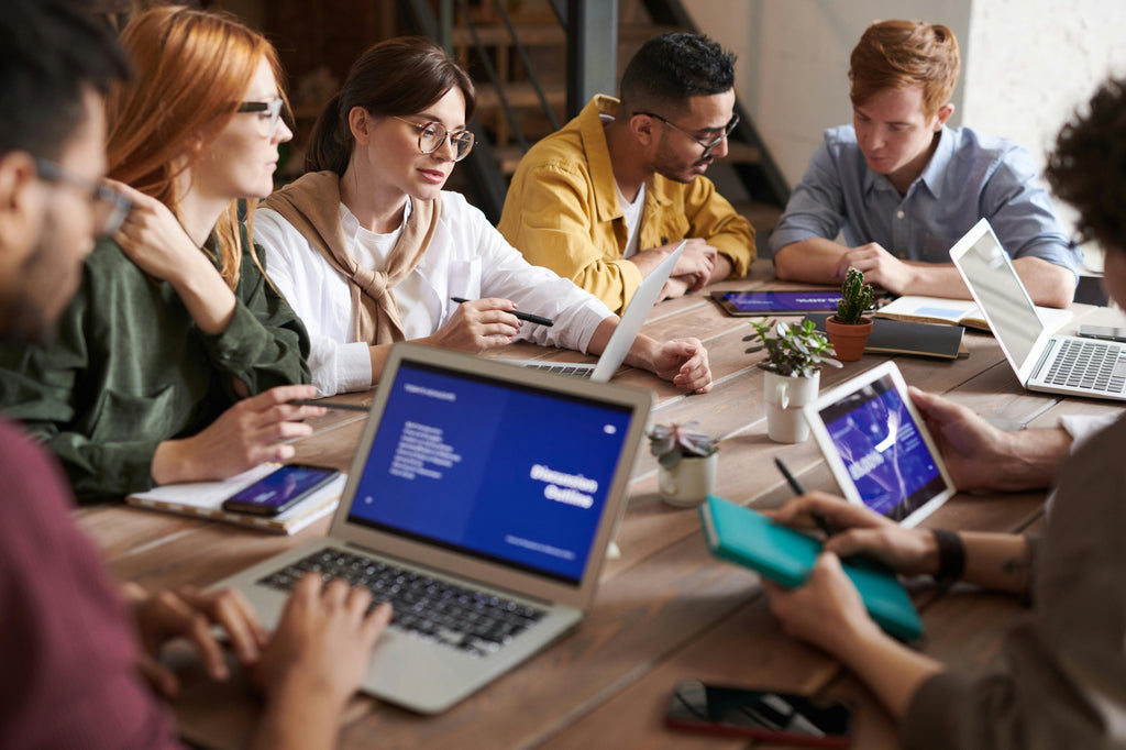 Group of Young Gen Z Coworkers at a Table on Laptops Working