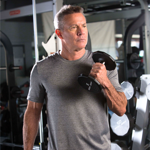 Middle aged man lifting weights in a gym.