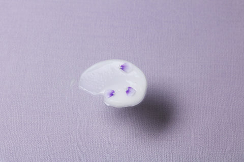 swatch of Bakuchiol Smoothing Serum with tiny purple petals