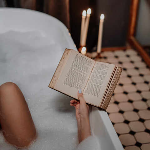 woman relaxing in bath with book