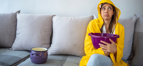 Woman holding a bucket under a leaking roof 