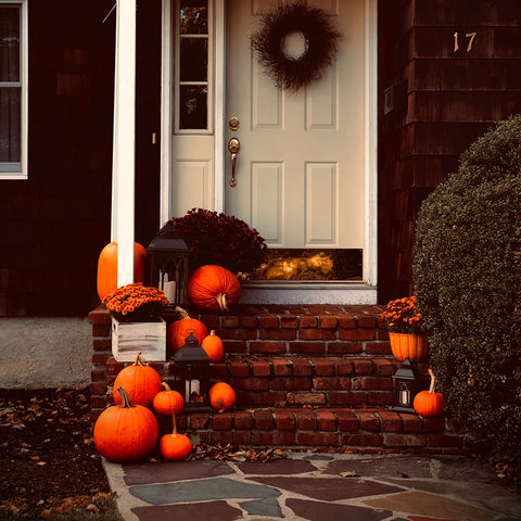 Halloween is here and the stairs in front of houses are decorated with pumpkins of different sizes and flowers .
