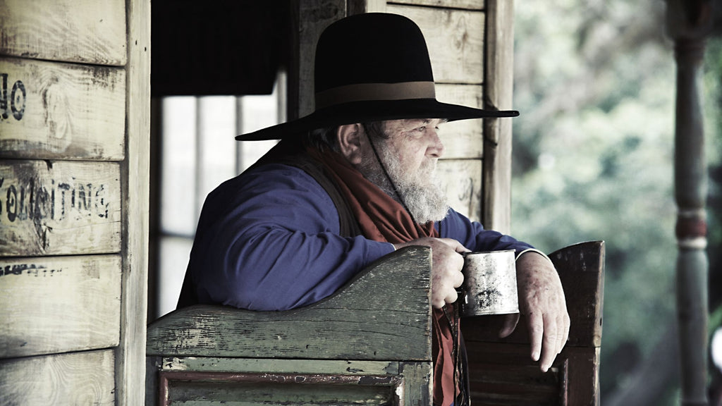 A cowboy holding a cup of aerial resupply coffee outside