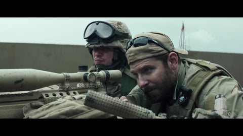 Chris Kyle, Navy Seal, laying on a rooftop with a rifle in the movie American Sniper