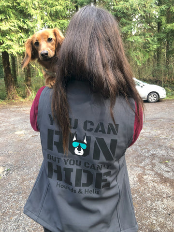 Girl with brown hair with her back to the camera holding dog looking over her shoulder at the camera