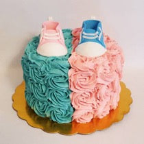 Unique Gender Reveal Cake with half blue and pink frosting & little blue and pink shoes on top