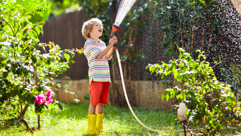 Boy Watering His Garden With A Hose