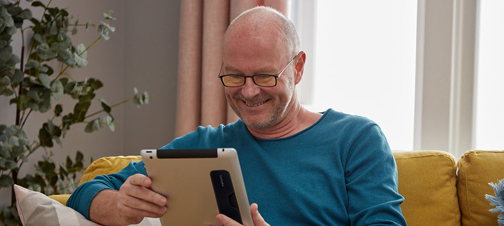 Man wearing Connect Blue Light Blocking Reading Glasses while using a tablet with the Connect Case attached to the tablet