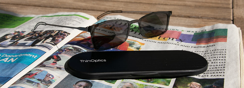 Brooklyn Reading Glasses with Milano Case sitting outside on top of a newspaper