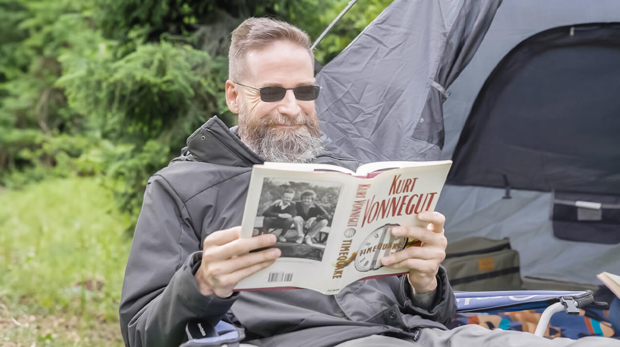 Man wearing Brooklyn Reading Sunglasses as he reads a book at a campsite