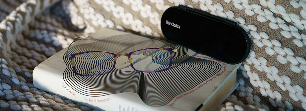 A pair of Brooklyn Reading Glasses with the Milano Case on top of a book