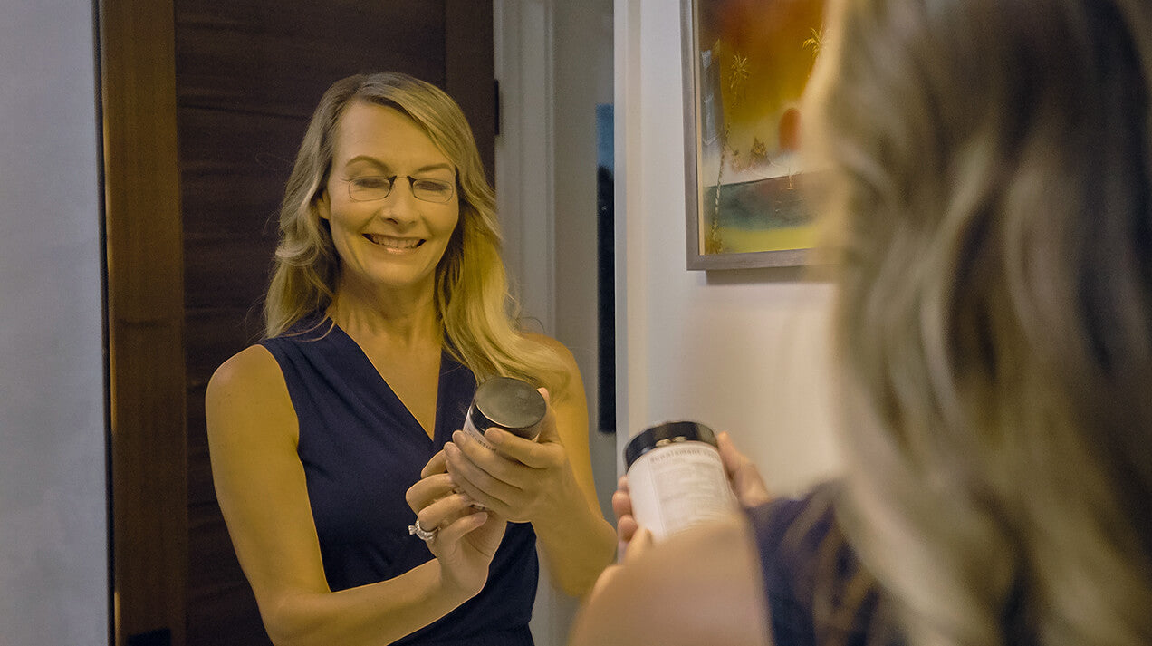 Woman wearing Readers while looking at the label on a bottle of supplements