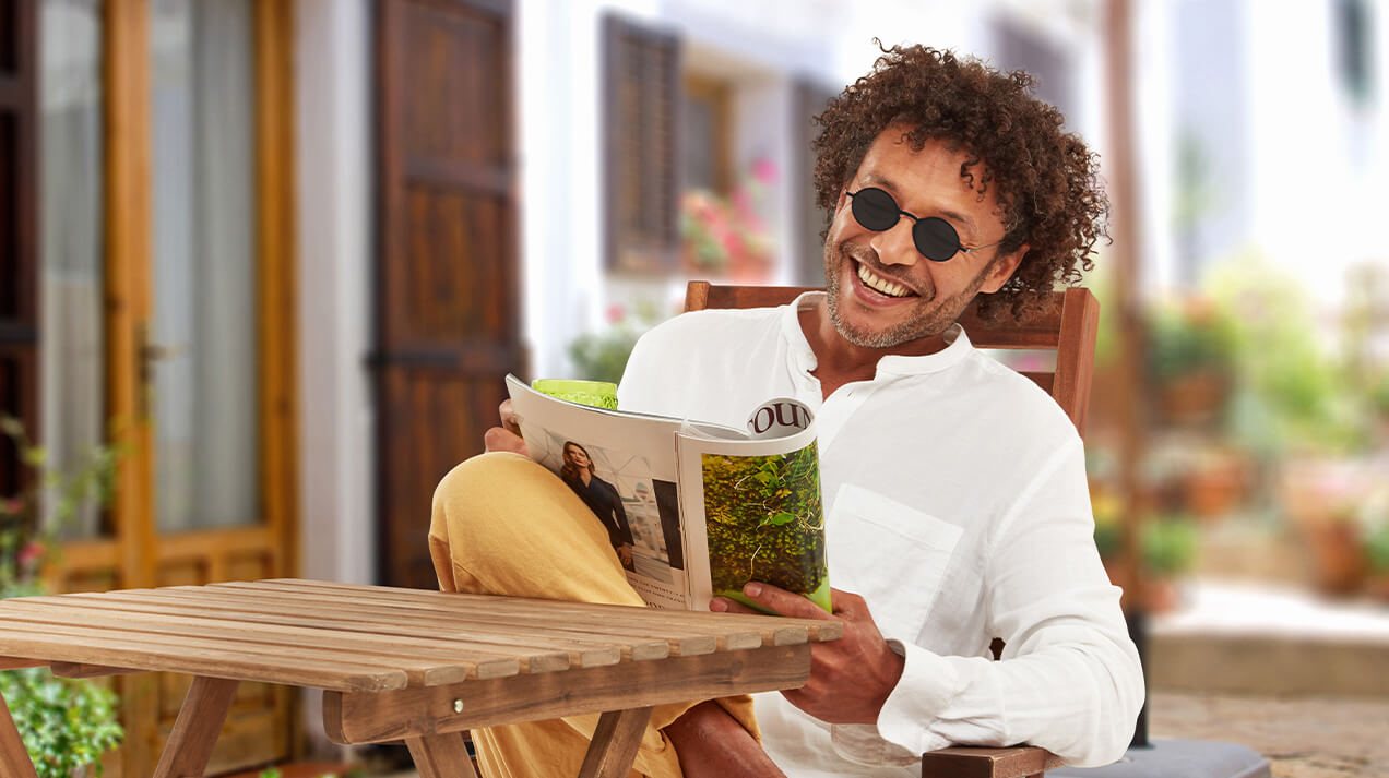 Man wearing Manhattan Reading Sunglasses while sitting outside reading a magazine