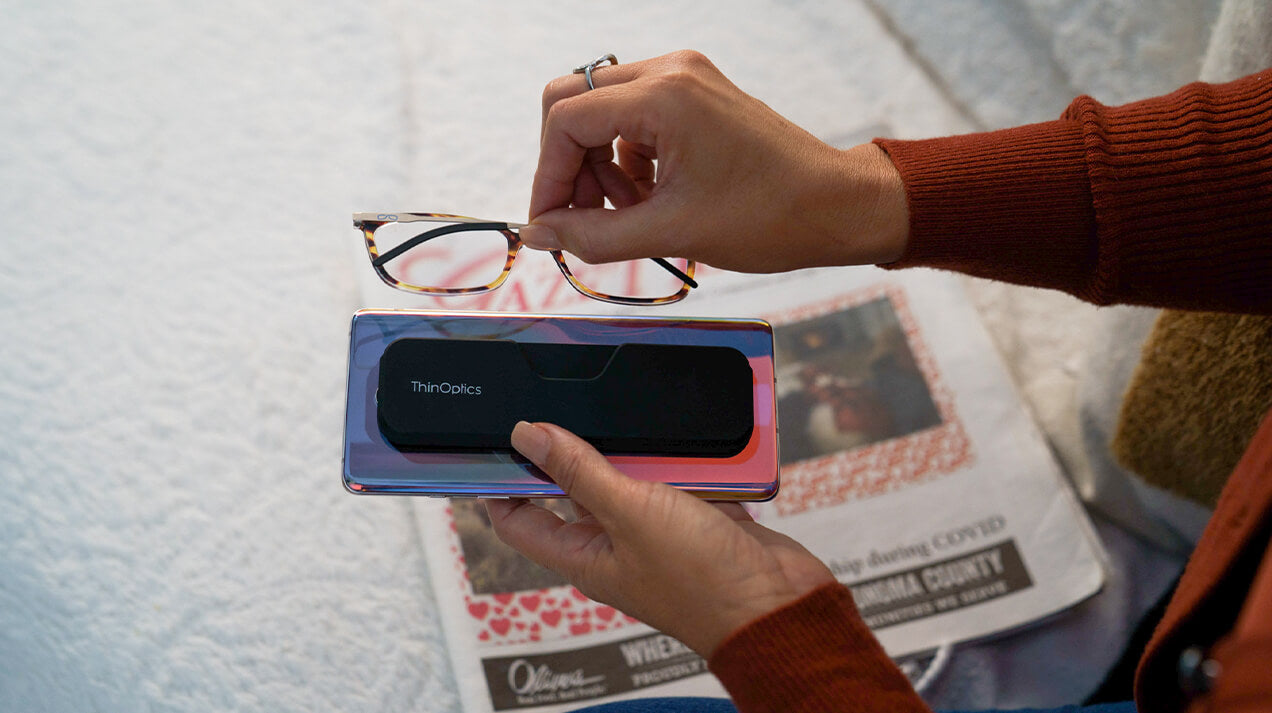 Woman removing Connect Reading Glasses from the Connect Case on the back on a mobile phone
