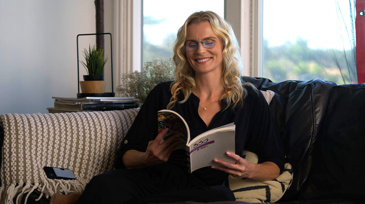 Woman wearing Limited Edition Ocean Mist Spring Bloom Collection Readers while reading a book.
