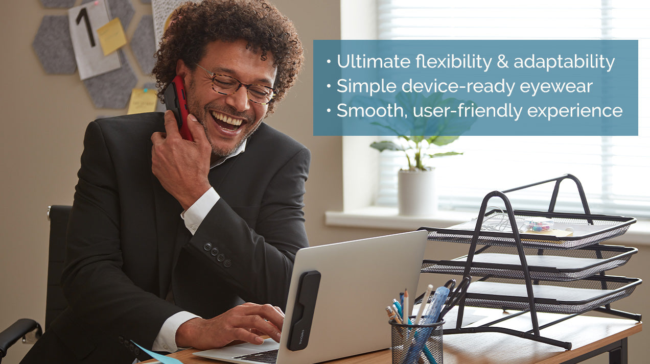 Man wearing Reading Glasses while talking on the phone and looking at his laptop. "Ultimate flexibility & adaptability. Simple device-ready eyewear. Smooth, user-friendly experience."